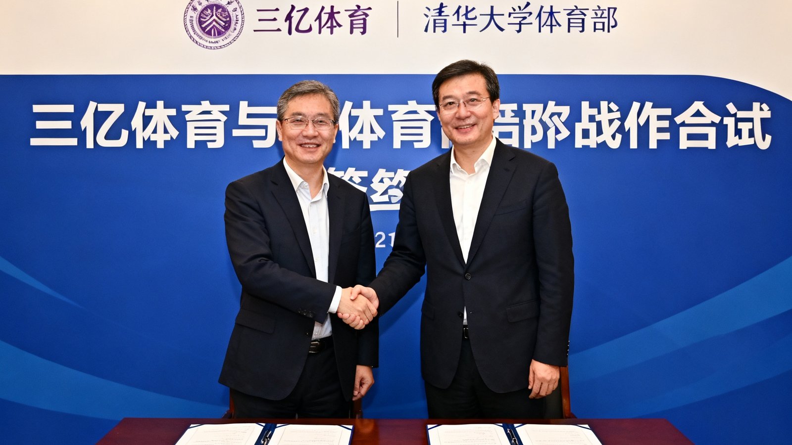 三亿体育与清华大学体育部战略合作签约仪式现场，双方代表在装饰有双方标识的背景板前握手合影，桌上摆放着签署完毕的合作协议文件